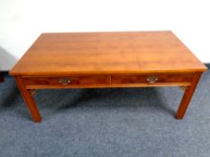 A yew wood coffee table on raised legs fitted with two drawers,