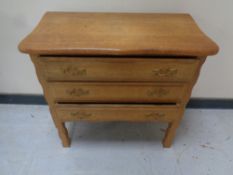A continental oak three drawer chest on raised legs