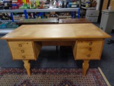 A blonde oak twin pedestal writing desk fitted six drawers
