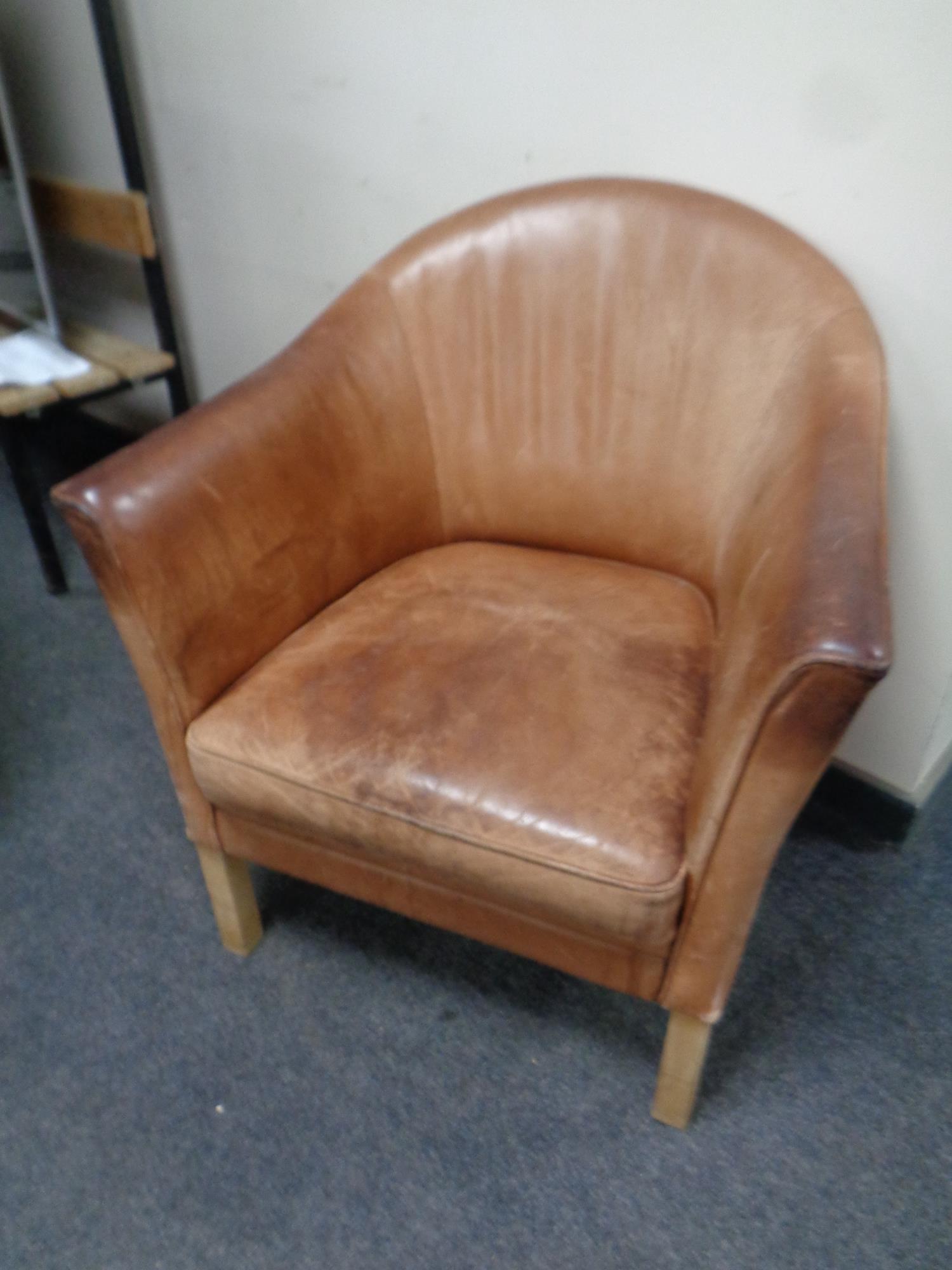 A tub chair upholstered in brown leather