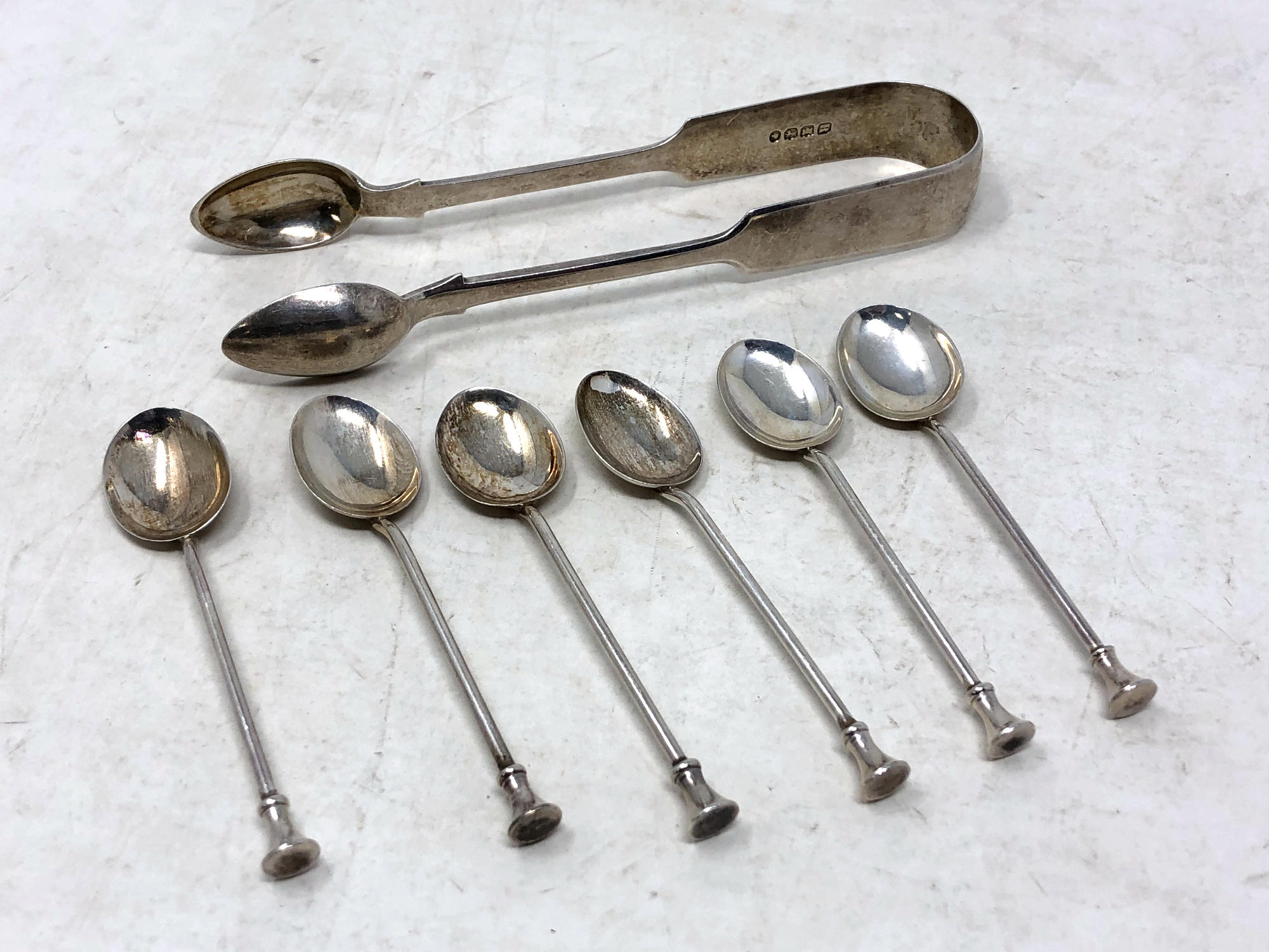 A set of six coffee spoons, together with a set of silver sugar tongs.