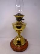 A brass Duplex oil lamp with glass chimney on a wooden stand