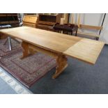 A blonde oak refectory dining table with extension leaves