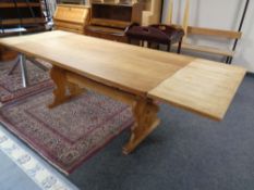 A blonde oak refectory dining table with extension leaves