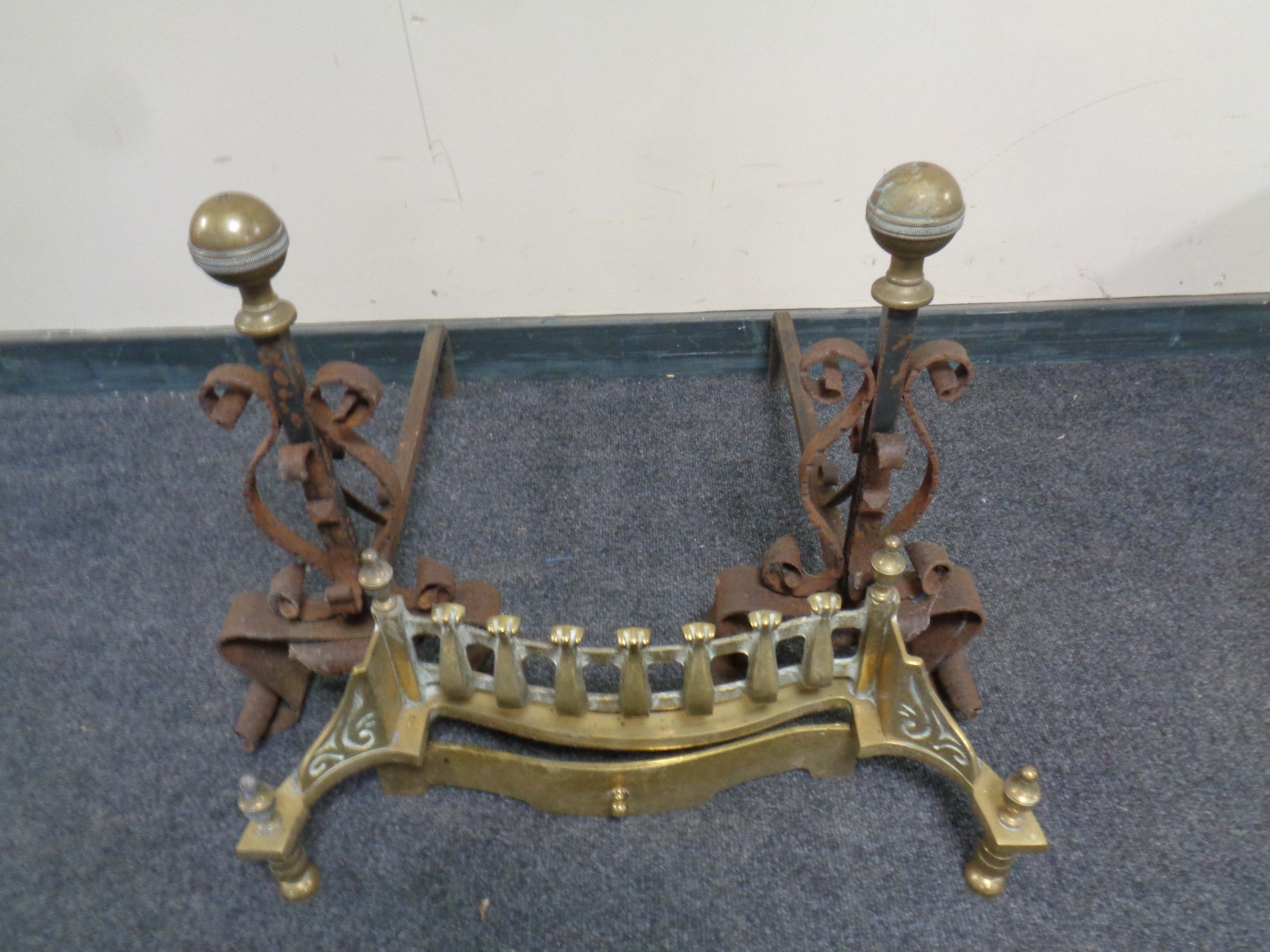 A pair of 19th century wrought iron and brass fire dogs together with a brass fire front