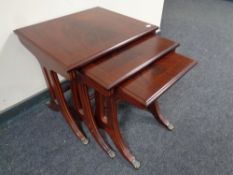 A nest of three good quality inlaid mahogany tables on brass capped feet