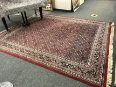 A Persian design carpet on red ground,