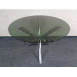 A contemporary circular smoked glass topped dining table on a metal tripod base