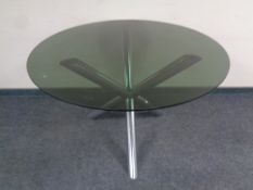 A contemporary circular smoked glass topped dining table on a metal tripod base