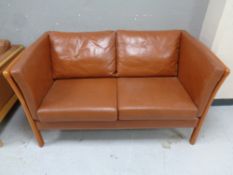 A 20th century Scandinavian wood framed settee upholstered in brown leather