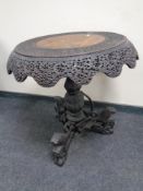 A 19th century heavily carved hardwood Burmese occasional table on three way pedestal