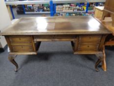 A 20th century carved oak French style writing desk fitted five drawers on cabriole legs
