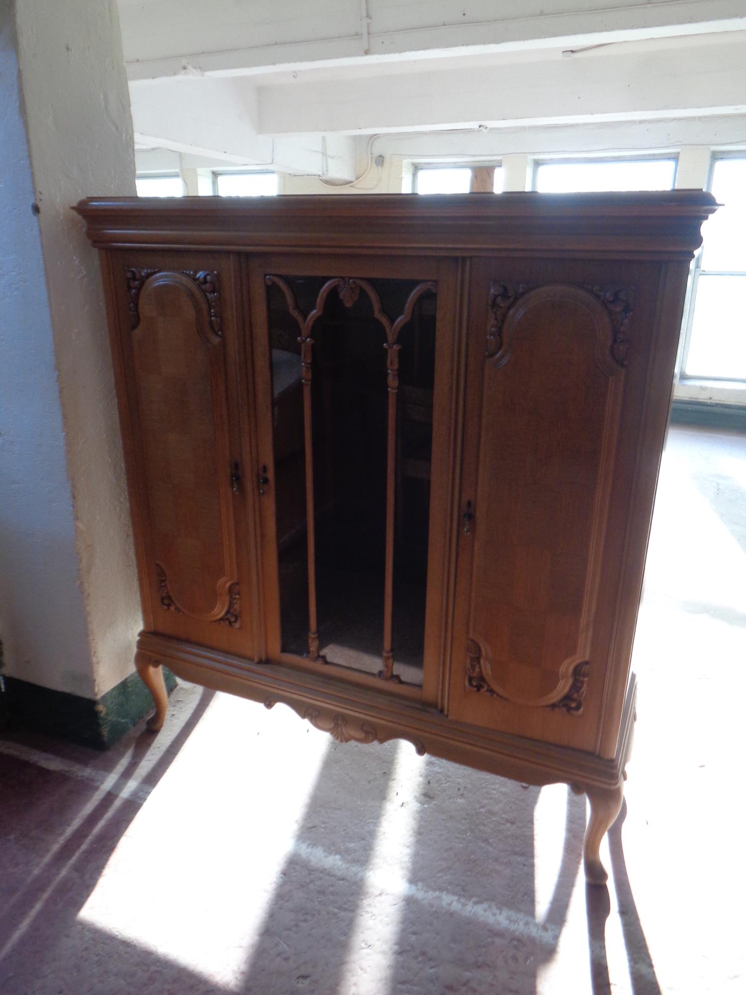 A 20th century continental oak triple door sideboard on raised cabriole legs