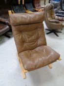 A Scandinavian beech framed lounge chair upholstered in a brown button leather