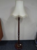 A carved beechwood standard lamp with tasselled shade