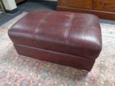 A contemporary storage footstool upholstered in Burgundy leather