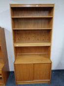 A set of mid 20th century teak open bookshelves fitted sliding door cupboard below,