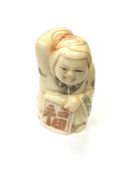 A Japanese carved bone netsuke - Lady in kimono holding a scroll.