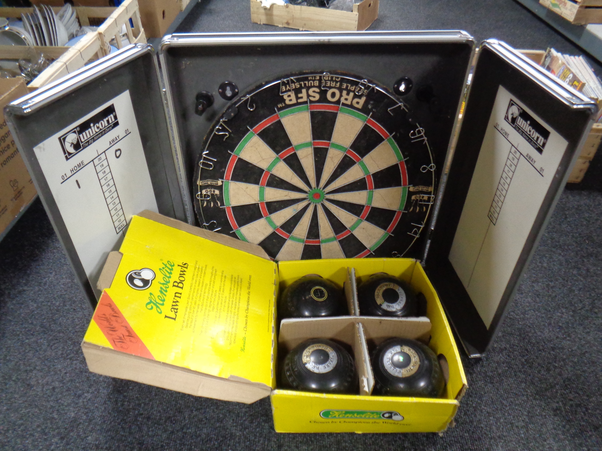 A Unicorn dartboard in case together with a boxed set of four Henselite lawn balls