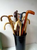 A plastic stick pot containing assorted walking sticks and parasols