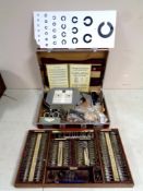 A case and a tray containing vintage optometrist's equipment