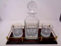 A lead crystal cut glass whisky decanter and two whisky glasses on wooden stand with brass gallery