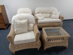 A four piece rattan conservatory suite with beige cushions comprising of two seater settee,