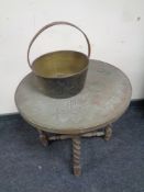 An eastern copper topped table on a folding barley twist stand together with an antique brass cast