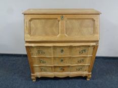 A continental blonde oak serpentine fronted writing bureau fitted three drawers,