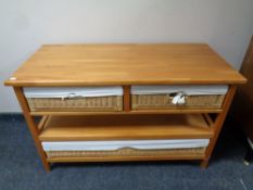 A contemporary pine three tier side table fitted with three wicker drawers