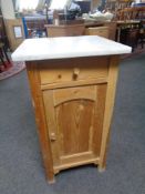 An early 20th century stripped pine marble topped bedside cabinet fitted a drawer