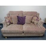 A Victorian style two seater settee upholstered in a gold and maroon striped fabric