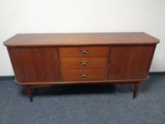 A 20th century teak D-shaped low sideboard with sliding shutter doors and three central drawers