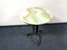 A circular onyx topped table on cast iron base,