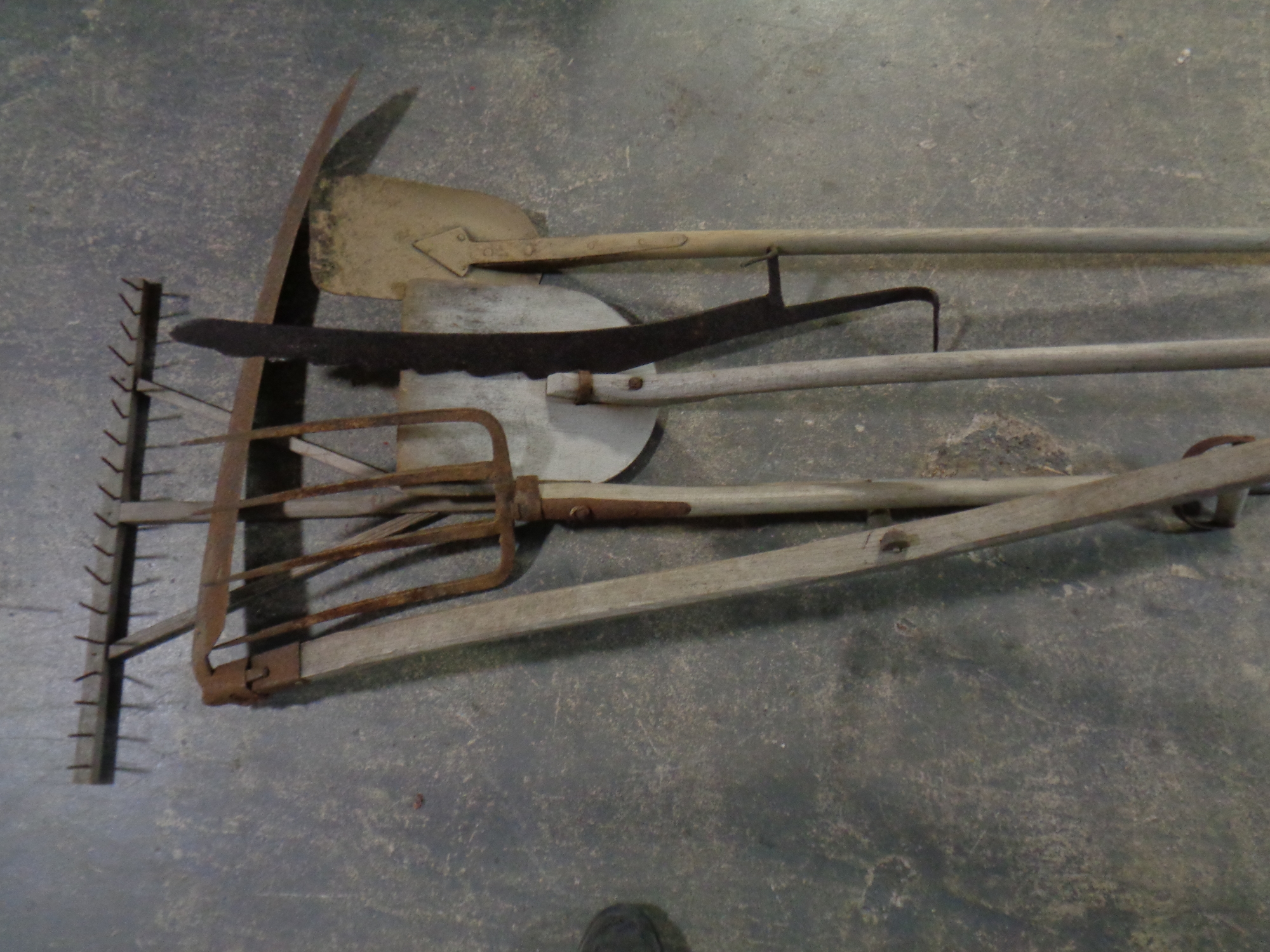 A bundle of farming tools including hay fork, scythe,