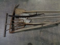 A bundle of farming tools including hay fork, scythe,