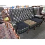 A three seater Chesterfield style wingback settee upholstered in green leather and fabric
