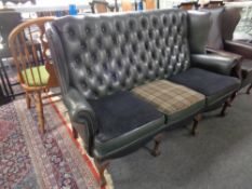 A three seater Chesterfield style wingback settee upholstered in green leather and fabric