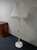 A painted standard lamp with tassel shade