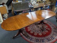 A Regency style inlaid mahogany twin pedestal dining table with leaf
