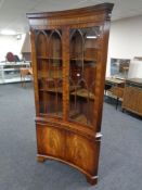 A reproduction mahogany inverted bow-front corner cabinet