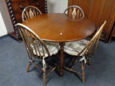 A circular oak dining table and four wheel back chairs,