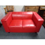 A two seater settee upholstered in red leather