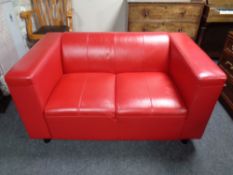 A two seater settee upholstered in red leather