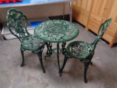 A cast metal patio table with two chairs