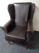 A wingback armchair upholstered in brown vinyl