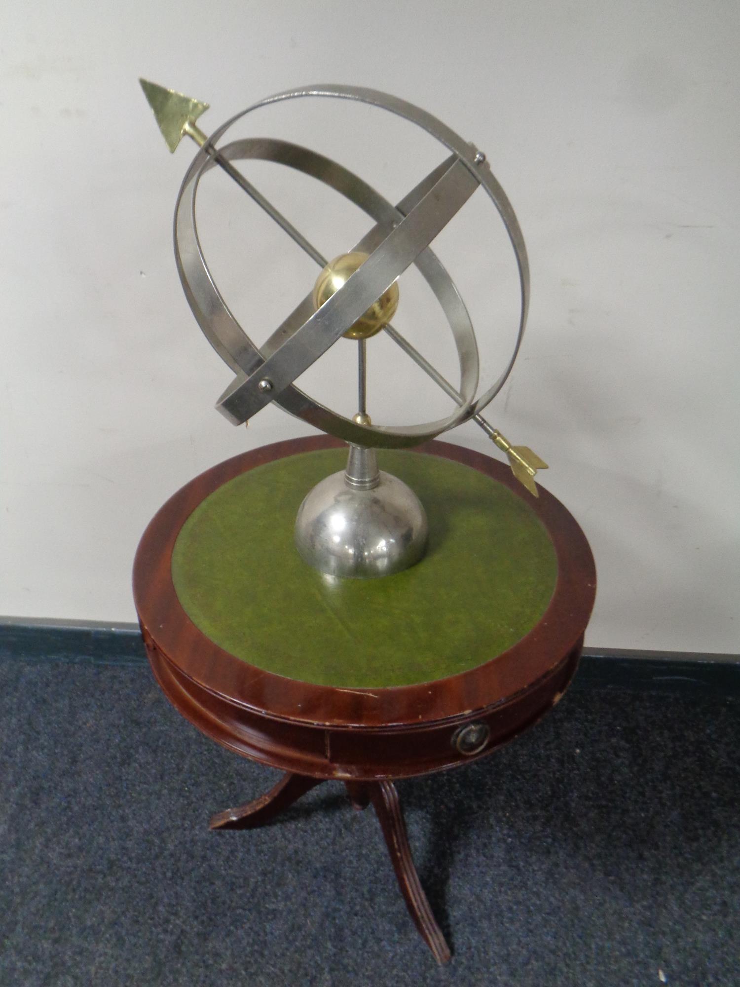 An armillary sphere together with a circular pedestal drum table with green leather inset panel