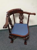 A carved reproduction corner armchair on claw and ball feet