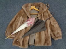 A mink fur coat together with two parasols