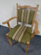 A blonde oak armchair in green striped fabric